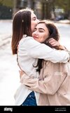 meeting-of-two-girls-friends-with-hug-in-city-2BYMB9T.jpg