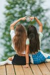 back-view-of-young-girls-sit-on-a-terrace-at-a-height-in-the-mountains-against-the-backdrop-of...jpg